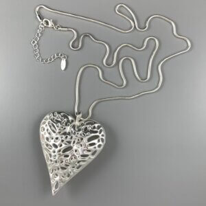 Large matt silver filigree heart pendant hanging from a silver snake chain